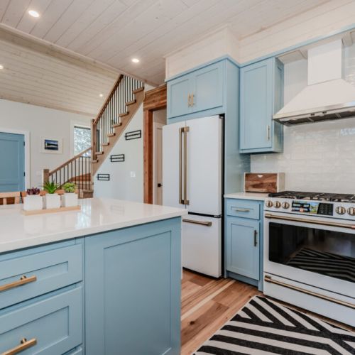 This bright and stylish cottage kitchen offers modern appliances, a spacious island, and charming details—perfect for preparing meals during your relaxing lakefront getaway or weekend vacation rental experience.