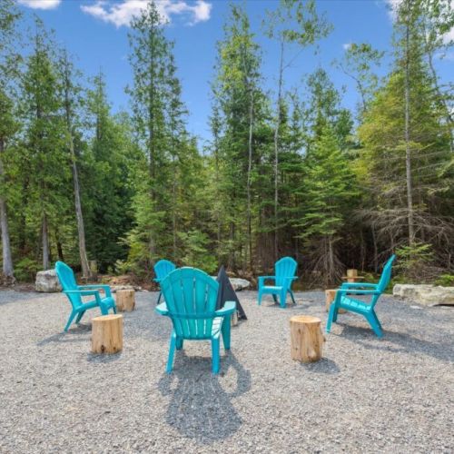 Gather ‘round the fire — this woodland clearing features vibrant Adirondack seating and rustic log stools, perfect for storytelling, stargazing, and s’mores under the trees.