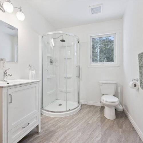 Spacious 3-piece bathroom with a walk-in shower, bright finishes, and natural light from the window.