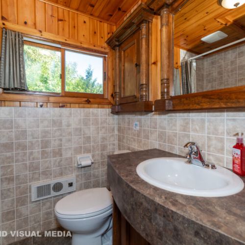 Bright and cozy bathroom featuring a full tub/shower, plenty of storage, and a warm wood finish.