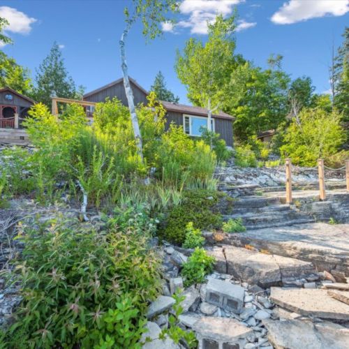 Natural stone steps wind through lush greenery, guiding you from the shoreline up to your lakeside retreat.
