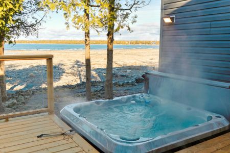 Your lakeside escape: Warm water, fresh air, and steam rising against a beautiful lake backdrop—the perfect invitation to slow down and enjoy cottage life.