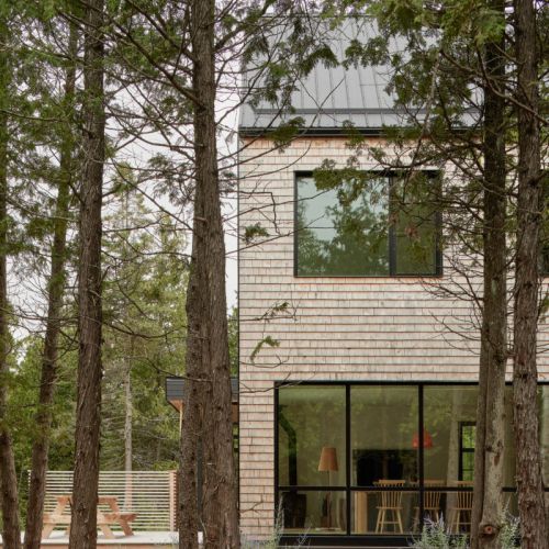 A modern exterior with natural wood siding and expansive windows that bring in plenty of natural light and forest views.
