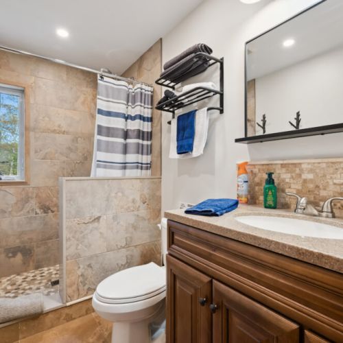 The main bathroom features a spacious, light-filled shower with a window for a bright, refreshing atmosphere. A full set of towels is provided for your stay, including bath, hand, and face towels for your comfort.