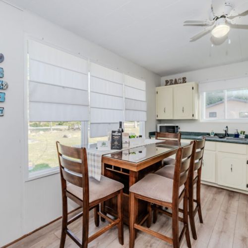 Bright eat-in kitchen with panoramic windows, cottage décor, and all essentials for your culinary needs—ideal for relaxed vacation dining.