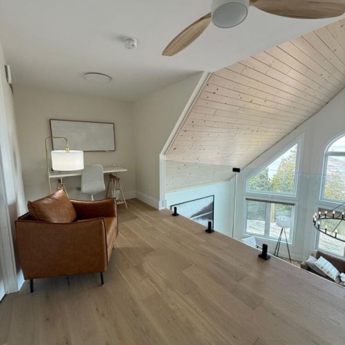 A bright upper-level nook with a desk and lounge chair, ideal for working remotely or relaxing with a view of the lake.