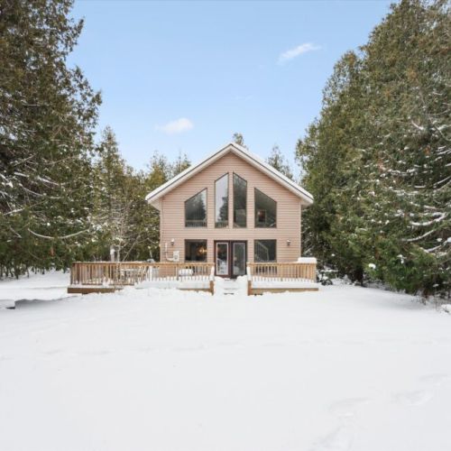 Spacious front exterior with expansive deck and stunning forest setting