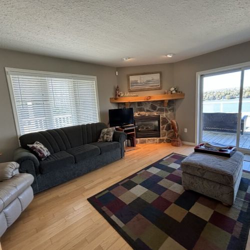 The living room is designed for leisure and lake gazing, complete with a cozy fireplace and comfortable seating for serene days in.