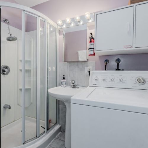 This bright and clean bathroom includes a modern shower and the convenience of an in-unit washer and dryer—perfect for longer stays.