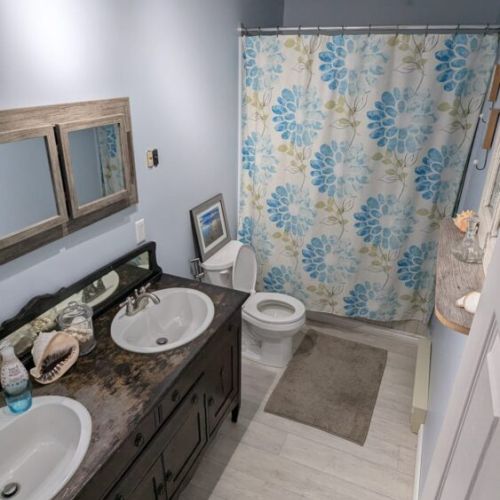 Additional full bathroom with double vanity and shower/tub combination.