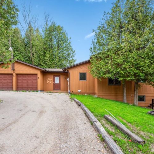 Welcome to By The Bay Getaway – your private lakeside retreat with a spacious double garage, ample parking, and a cozy, rustic charm surrounded by towering cedars.