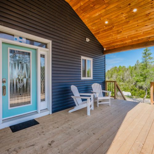 The elegant entrance features a charming turquoise door with intricate glasswork, leading into the spacious and welcoming interior. The wood-paneled ceiling adds a touch of rustic charm to this modern entryway.