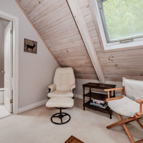 Tucked away under sloped ceilings, this peaceful nook offers a serene spot to relax with a window view of the natural surroundings.