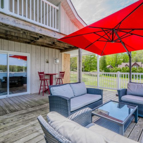 Another view of the deck highlights its spaciousness and inviting setup. With a small dining table and chairs, it's a perfect spot for alfresco dining, surrounded by the beauty of the lakefront scenery.