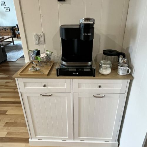 A convenient coffee station with a Keurig machine, coffee essentials, and a neat storage cabinet, adding a practical touch to the cozy cabin.