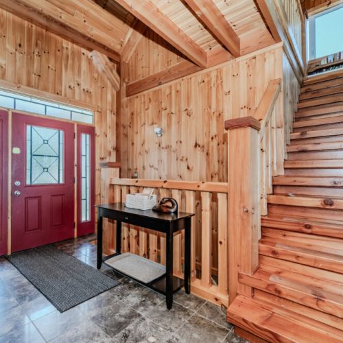 Welcoming front entrance with grand red doors, wood detailing, and a spacious staircase—setting the tone for a charming and relaxing cottage escape.