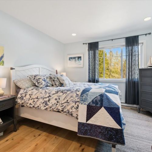 Rest comfortably in this bright and inviting bedroom, featuring a cozy queen bed and peaceful views of the surrounding trees.