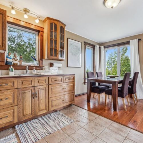 Bright and welcoming, the open kitchen flows into a dining nook surrounded by forest-view windows—perfect for cozy meals and conversation.