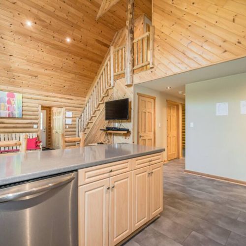 Entertain the whole family from the kitchen area.  The open-plan living space blends seamlessly with the rugged beauty of the log walls and expansive ceilings, offering a perfect gathering spot for guests seeking the warmth of rustic elegance after a