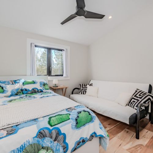 This airy bedroom offers a queen bed and futon seating, ideal for family stays or group getaways. Natural light and minimalist decor create a serene space for your vacation escape.