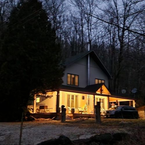 Porchlight & Pines glowing warmly in the evening forest setting.