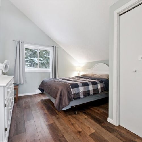 Cozy upstairs bedroom with queen bed, vaulted ceiling, and peaceful woodland views