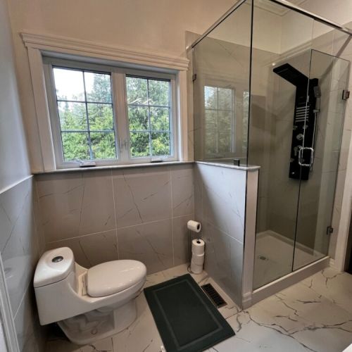 Bright bathroom with walk-in glass shower and views of the surrounding greenery