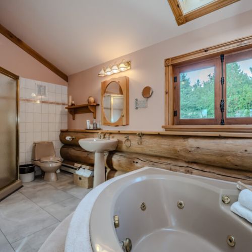 ndulge in spa-like luxury with a jetted soaking tub, separate glass-enclosed shower, and serene views of the surrounding greenery—perfect for unwinding after a day of adventure.