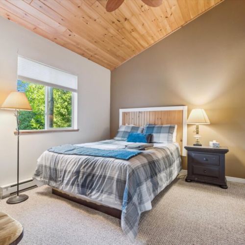 Peaceful main-floor bedroom with queen bed, cozy lighting, and forest views — a serene space for restful nights after exploring Tobermory.