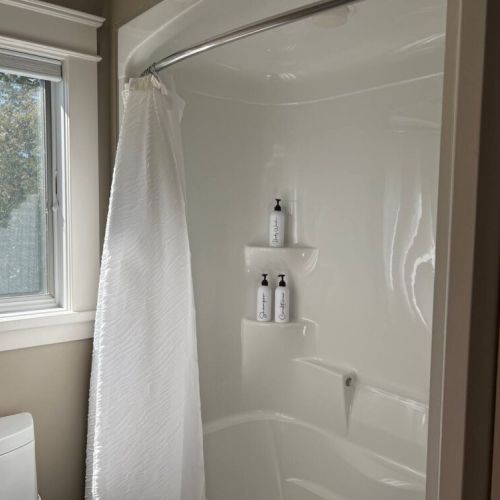 Bright bathroom with a clean and spacious shower area, featuring a large window for natural light—offering a fresh, modern feel.