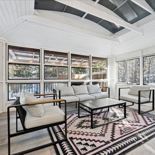 Bright screened-in porch lounge with comfortable seating and peaceful woodland views. A perfect space to read, relax, or enjoy a quiet moment away.