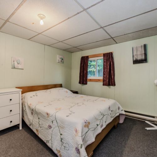 A serene bedroom with soft green walls, a cozy bed, and a fan for comfort.