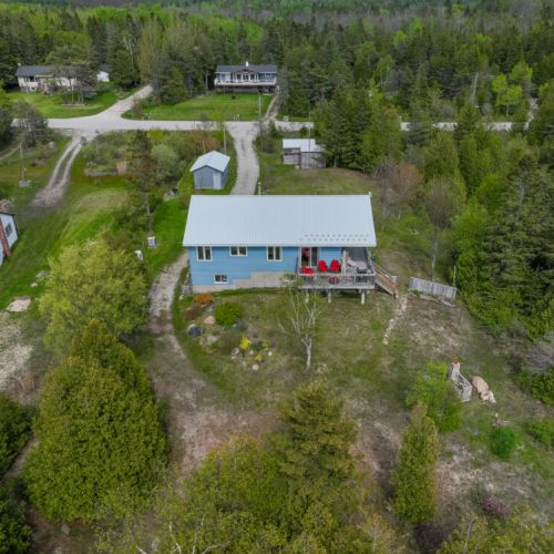 Private cottage retreat nestled in nature with a spacious yard, forest backdrop, and cozy deck—perfect for peaceful getaways on the Bruce Peninsula.