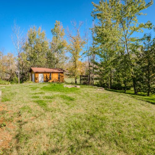 The expansive backyard is surrounded by mature trees and lush greenery, providing a peaceful and private outdoor space. There’s plenty of room for outdoor games, family gatherings, or simply enjoying the fresh air and natural beauty that surrounds the property.