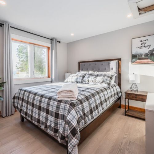 Upper level guest room with waterfront views. This bedroom combines the warmth of rich wooden furniture with the soft bedding to create a cozy space.