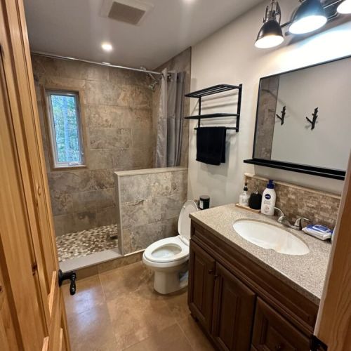 The main bathroom features a spacious shower complemented by a window, allowing for natural light and a refreshing ambiance during your bathing experience.