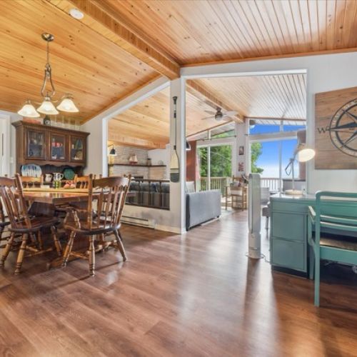 Bright dining area with warm wood ceilings, open layout, and scenic lake views — perfect for family meals and gatherings.