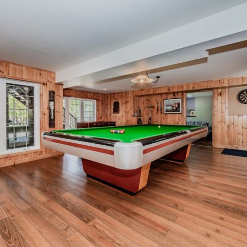 Enjoy cozy evenings in the wood-paneled games room featuring a full-size pool table and lounge space—perfect for indoor fun at your vacation rental.