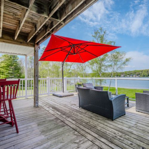 The expansive deck at Jack's Retreat offers a perfect spot for outdoor relaxation. Featuring comfortable seating and a vibrant red umbrella, this area is ideal for enjoying the lake view while sipping on a morning coffee or an evening drink.
