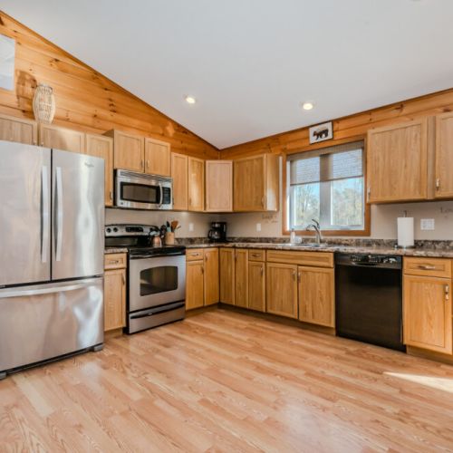 A warm, wood paneled kitchen with stainless steel appliances, ample cabinet space, and granite countertops. The open layout creates a cozy, inviting atmosphere.