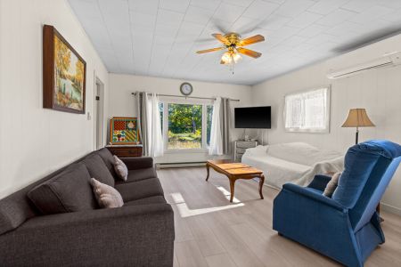 Bright and comfortable living room with plenty of seating, a flat-screen TV and large windows overlooking the peaceful property.