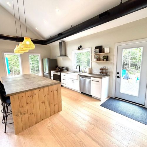 Fully equipped and beautifully designed – this modern kitchen has everything you need to cook up a feast, from stainless appliances to a large prep island and forest views.