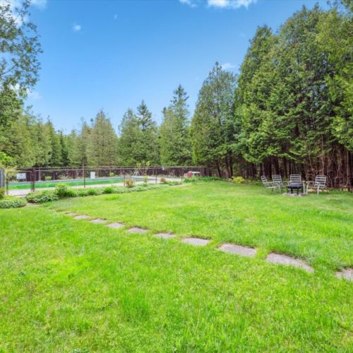 A wide green yard invites lawn games, garden strolls, and carefree lounging. Stone steps lead you to the pool, fire pit, and forest—all just steps from the cottage.