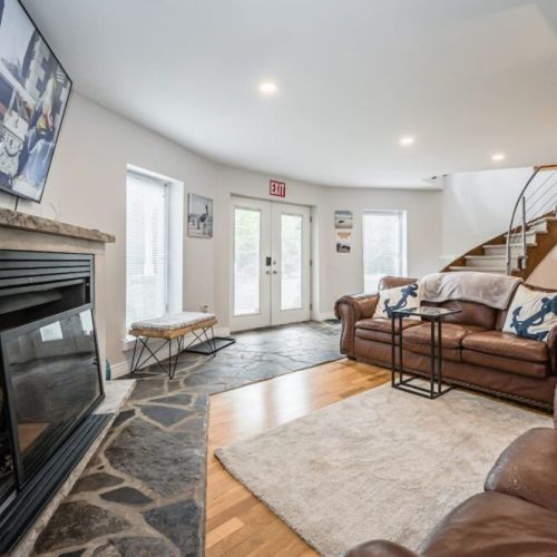 The main living area with smart TV and fireplace, and staircase to the upper Great room and bedrooms.