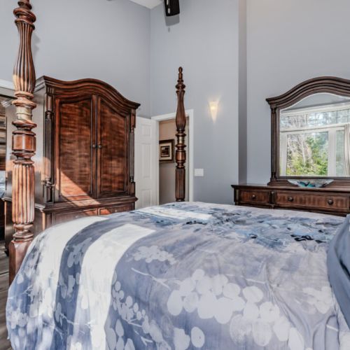 Elegant primary bedroom with classic wood furnishings, large windows, and serene views—an inviting retreat for travellers seeking a peaceful and luxurious stay in this charming vacation rental.