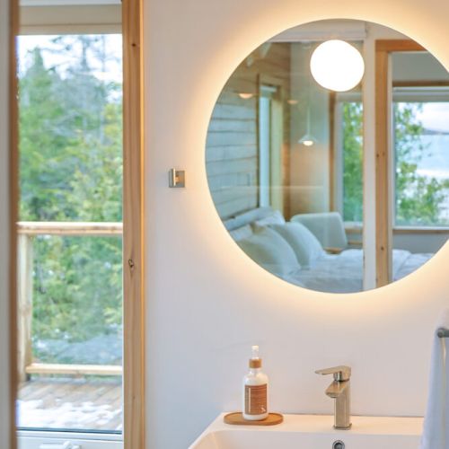 Experience the epitome of modern elegance in this beautifully designed bathroom. The circular mirror and sleek fixtures create a sophisticated and inviting atmosphere.