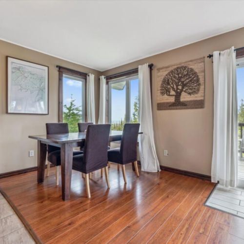 Bright dining space with seating for six, surrounded by large windows offering tranquil forest views.