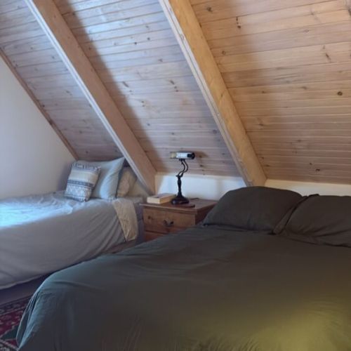 This charming attic bedroom features sloped ceilings and warm wooden accents, offering a cozy and inviting space to recharge. Perfect for those seeking a peaceful and rustic touch during their Georgian Bay getaway.