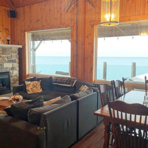 The open-concept living room, with floor-to-ceiling windows, offers breathtaking views of the bay, creating a cozy yet spacious area for relaxation.