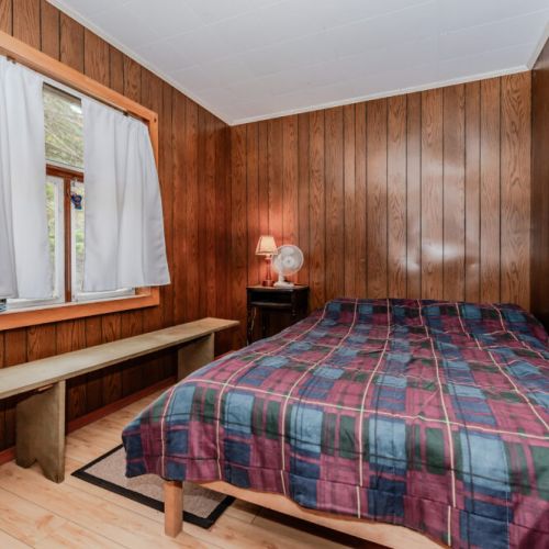 Charming second bedroom with cozy bedding and natural wood finishes—perfect for families, couples, or groups seeking a relaxing country retreat.